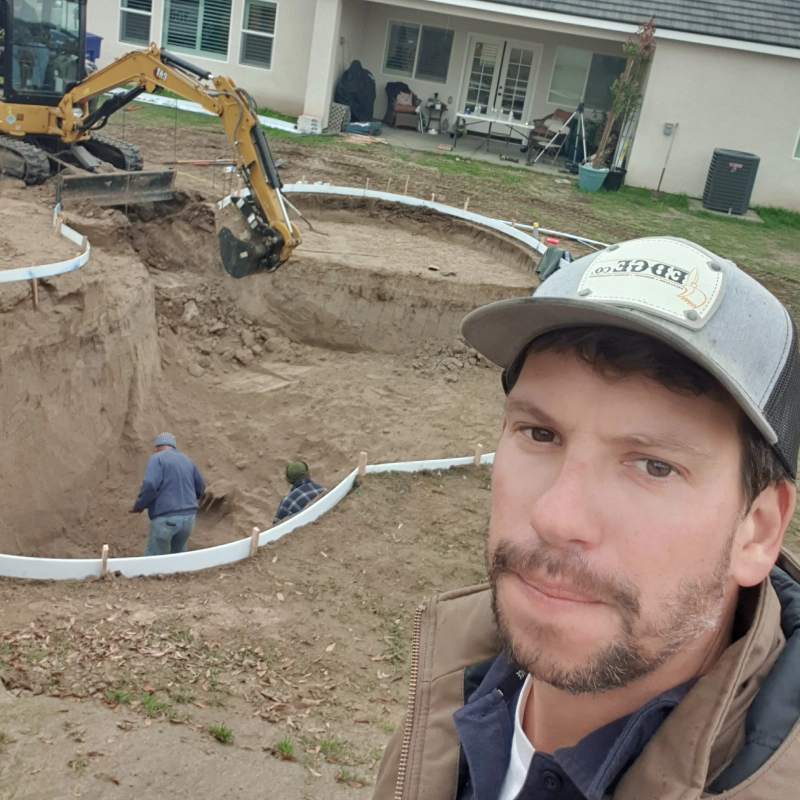 workers excavating a pool outside of a house on a patio